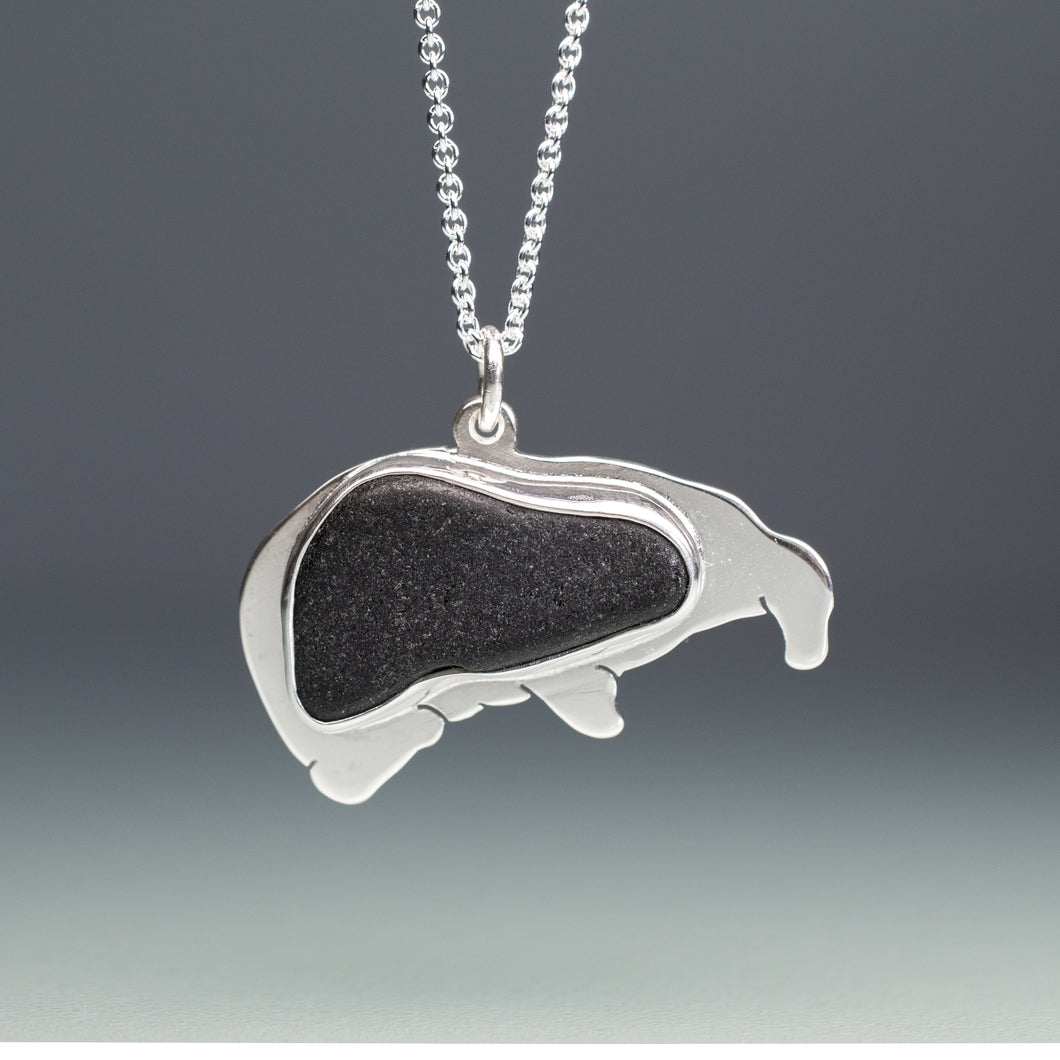 Silver pendant with a black sea glass on a gray background