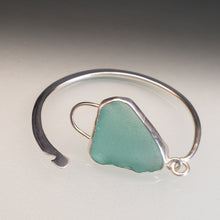Load image into Gallery viewer, A sterling silver cuff bracelet featuring a rough, organic-shaped light green sea glass stone, displayed on a neutral gray background.
