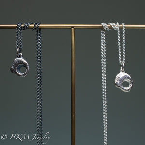 close up of hag stone necklaces cast in sterling silver by hkm jewelry in oxidized and polished finishes