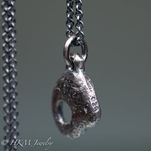 close up of stamping on hag stone necklace cast in sterling silver by hkm jewelry in oxidized finish