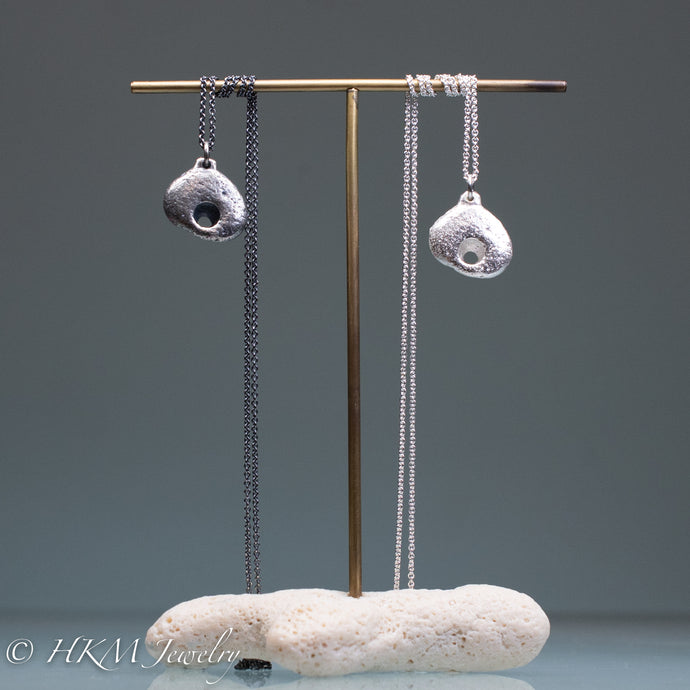 hag stone necklaces cast  in sterling silver by hkm jewelry on brass and coral jewelry stand