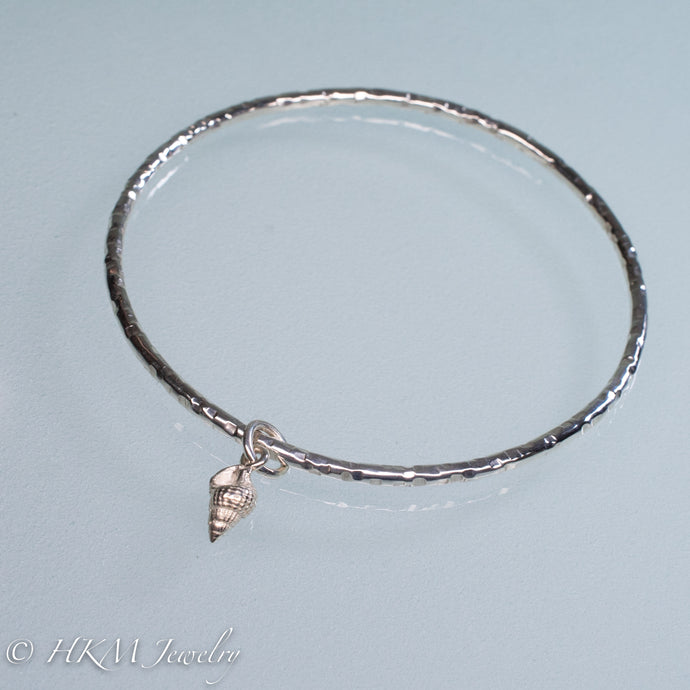 hammered silver bangle with mud snail shell charm by hkm jewelry