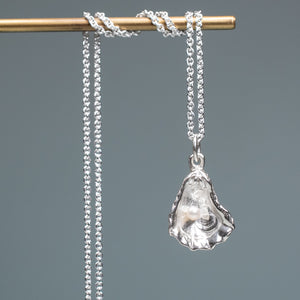 Silver pendant necklace on a gray background hkm jewelry oyster pearl necklace kittens paw