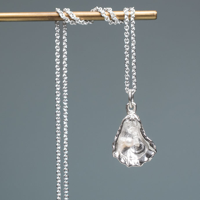 Silver pendant necklace on a gray background hkm jewelry oyster pearl necklace kittens paw