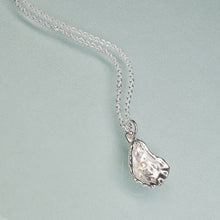 Load image into Gallery viewer, Silver necklace with an oyster pendant on a light blue background

