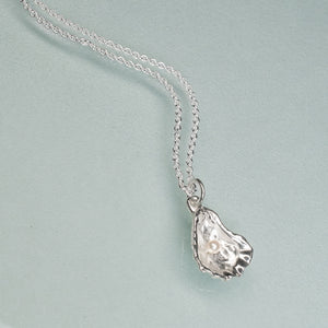 Silver necklace with an oyster pendant on a light blue background