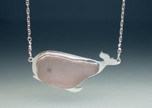 Load image into Gallery viewer, A whale-shaped pendant necklace made of polished silver with a smooth, matte dusty pink stone inlay, suspended from a silver chain with small pearl-like beads.
