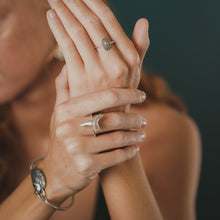 Load image into Gallery viewer, Close-up of a person's hands with rings and a bracelet on a blurred background
