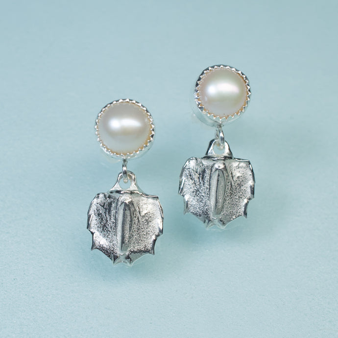 cast silver mantis shrimp tail and pearl two tier dangle earrings on blue background