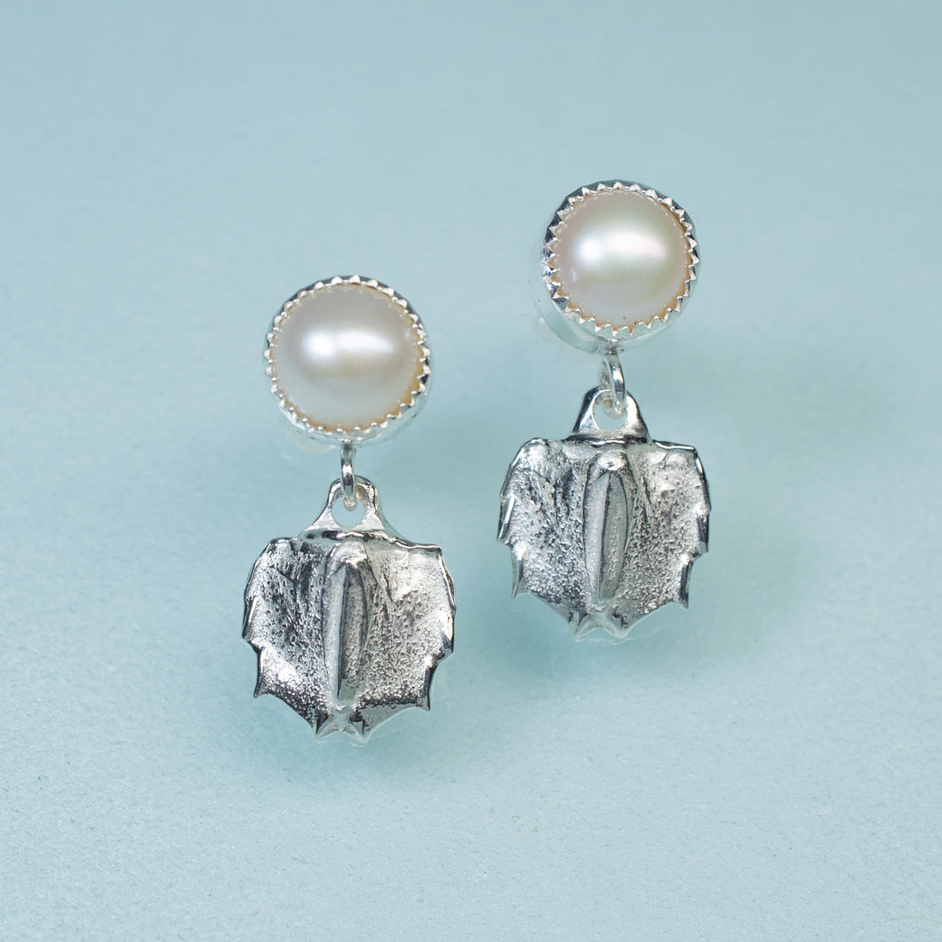 cast silver mantis shrimp tail and pearl two tier dangle earrings on blue background