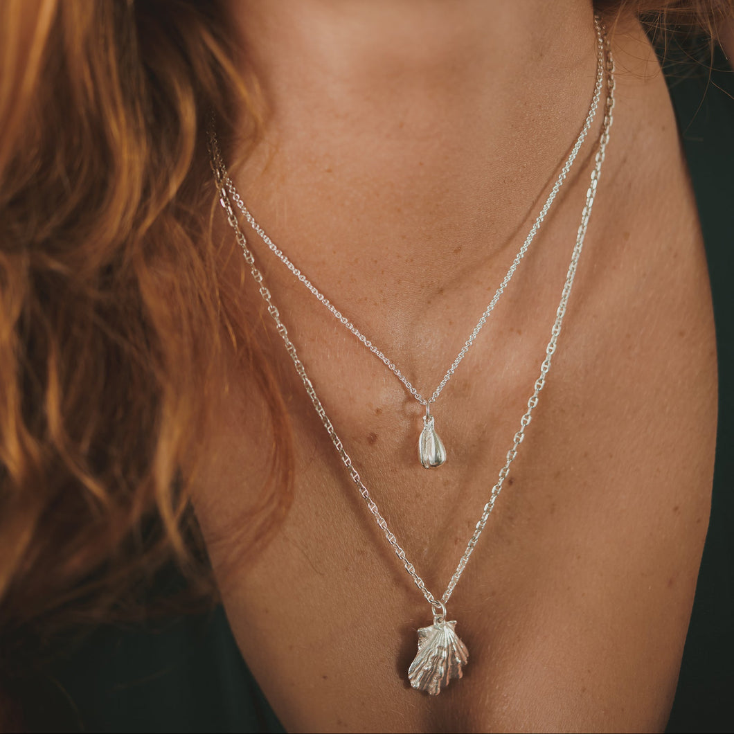 Female, red-head, kitten’s paw necklace, marginella shell necklace, cropped close up