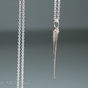 close up of mini horseshoe crab tail necklace in sterling silver by hkm jewelry