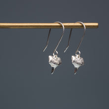 Load image into Gallery viewer, cast silver small shark tooth earrings on brass earring stand with blue gradient background
