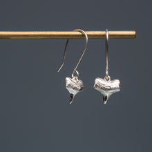 Load image into Gallery viewer, cast silver small shark tooth earrings on brass earring stand with blue gradient background
