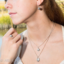 Load image into Gallery viewer, Close-up of a person wearing silver necklaces and earrings outdoors.

