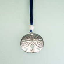 Load image into Gallery viewer, cast silver sand dollar ornament from stone harbor nj with freshwater pearl and navy blue satin ribbon by hkm jewelry on blue background
