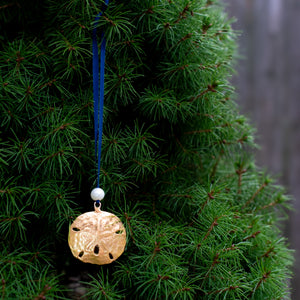 cast bronze sand dollar ornament from stone harbor nj with freshwater pearl and navy blue satin ribbon by hkm jewelry on evergreen tree