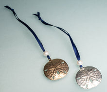 Load image into Gallery viewer, cast bronze and silver sand dollar ornament from stone harbor nj with freshwater pearl and navy blue satin ribbon by hkm jewelry on blue background
