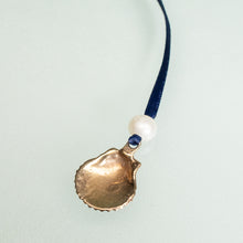 Load image into Gallery viewer, back of cast bronze scallop ornament with freshwater pearl and navy blue satin ribbon by hkm jewelry
