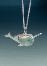 Load image into Gallery viewer, A sterling silver narwhal pendant necklace with a smooth, polished light green seafoam sea glass inlay, suspended from a silver ball chain against a dark blue gradient background.
