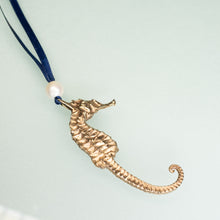 Load image into Gallery viewer, cast bronze seahorse ornament with freshwater pearl and navy blue satin ribbon by hkm jewelry
