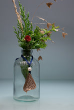 Load image into Gallery viewer, Clear glass bottle with dried plants and decorative elements on a light gray background
