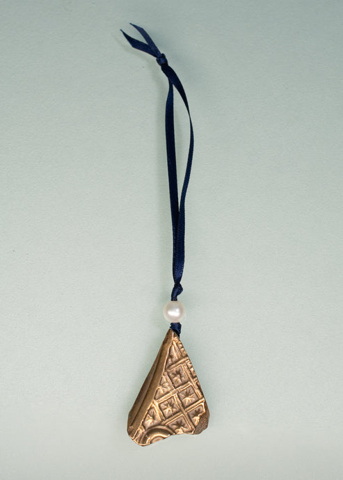 Bronze triangle-shaped ornament with a pearl and blue ribbon on a light gray background