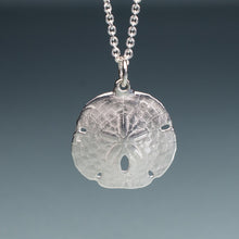 Load image into Gallery viewer, small silver sand dollar shell necklace on cable chain with blue gradient background
