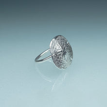 Load image into Gallery viewer, side view of silver sand dollar ring on blue green gradient background
