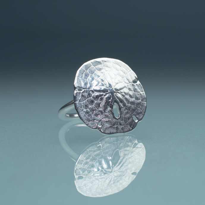 silver sand dollar ring on blue green gradient background