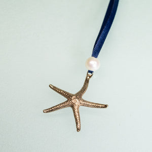 cast bronze starfish ornament with freshwater pearl and navy blue satin ribbon by hkm jewelry