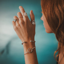 Load image into Gallery viewer, Close-up of a hand wearing multiple rings and bracelets against a blurred background
