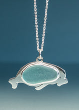 Load image into Gallery viewer, A silver-toned necklace featuring a sea turtle pendant with a smooth, polished light blue-green stone inlay, suspended against a dark teal-blue gradient background.
