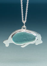 Load image into Gallery viewer, A silver manatee pendant necklace featuring a smooth, polished sea glass insert in a light teal-blue color, suspended from a silver ball chain against a dark blue gradient background.
