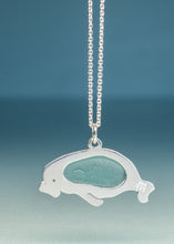 Load image into Gallery viewer, A silver whale pendant necklace featuring a smooth, light blue-green sea glass inlay, suspended from a silver ball chain against a soft blue gradient background.
