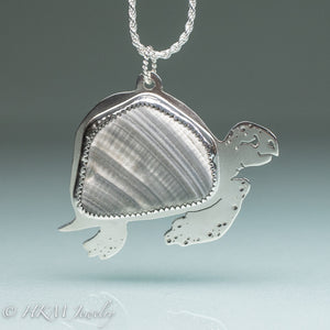 hand sawn and pierced sterling silver sea turtle necklace with fossilized clam shell shard bezel setting