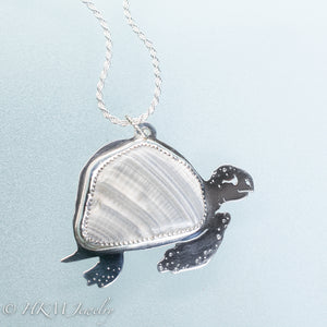 hand sawn and pierced sterling silver sea turtle necklace with fossilized clam shell shard bezel setting by hkm jewelry