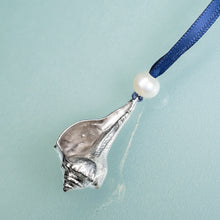 Load image into Gallery viewer, cast silver lightning whelk ornament from key west florida with freshwater pearl and navy blue satin ribbon by hkm jewelry on blue background
