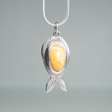 Load image into Gallery viewer, Silver fish necklace with a yellow stone on a gray background
