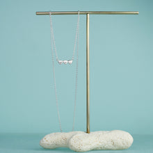 Load image into Gallery viewer, 3 little clams bar necklace on coral and brass stand
