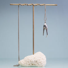 Load image into Gallery viewer, underside view of the cast fiddler crab claw necklace in recycled silver hanging from brass and coral necklace display on a blue background by hkm jewelry
