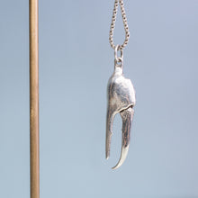 Load image into Gallery viewer, close up view of the cast fiddler crab claw necklace in recycled silver hanging from brass and coral necklace display on a blue background by hkm jewelry
